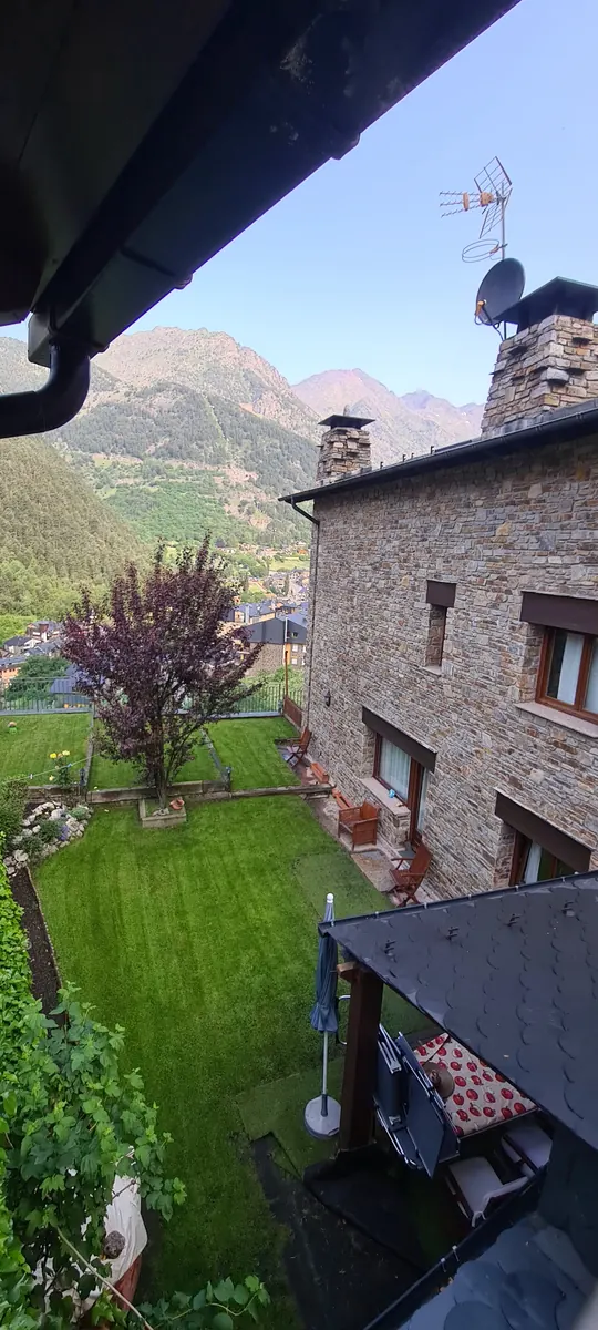 Chimenea sobre un tejado de pizarra con montañas al fondo.